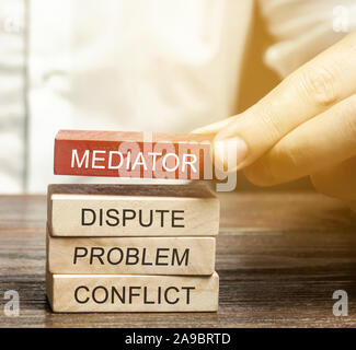 Ein Mann hält Holzblöcke mit dem Wort Mittler, Streit, Problem, Konflikt. Beilegung von Streitigkeiten durch Vermittler. Streitschlichtung und Mediation. Th Stockfoto