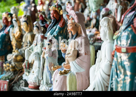 Hunderte von kleinen Statuen, die Götter der verschiedenen Religionen an einem Hügel in einem Coastal Park im Waterfall Bay, Hong Kong sitzen. Stockfoto