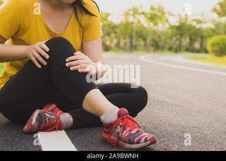 Knieverletzungen. Young Sport Frau knie Holding mit ihren Händen in den Schmerz nach Leiden Muskelverletzungen während eines laufenden Training im Park. Healthcare eine Stockfoto