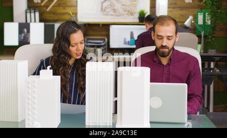 Designer arbeiten auf einem Laptop und Architec bei Blueprints in modernen Büro innen Stockfoto