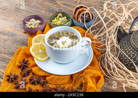 Kamille Tee in Gusseisen Teekanne. Kamille Tee Tasse, antiken chinesischen Gusseisen Teekanne, Zitrone und Sternanis auf einem Holztisch. Stockfoto