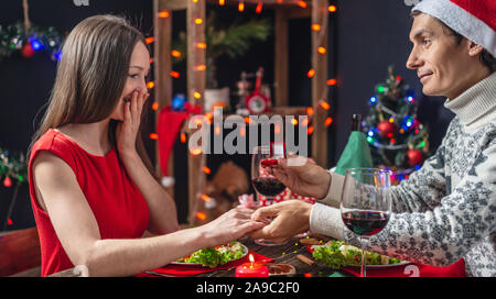 Eine junge schöne Paar Liebhaber verbringen Sie einen festlichen Abend. Ein Mann schlägt Ehe mit seiner Geliebten und gibt einen Verlobungsring am Heiligabend Stockfoto