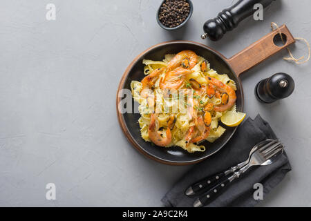Reginelle Pasta Spaghetti mit Meeresfrüchten, Krabben, Muscheln schwarz auf grau Tabelle, Ansicht von oben. Traditionelles Gericht in Italienisch. Stockfoto