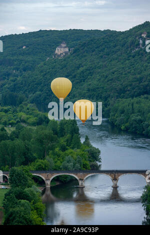 Zwei gelben Heißluft-ballons Fliegen über den Fluss Dordogne mit Chateau castlenaud im Hintergrund Dordogne Frankreich Stockfoto