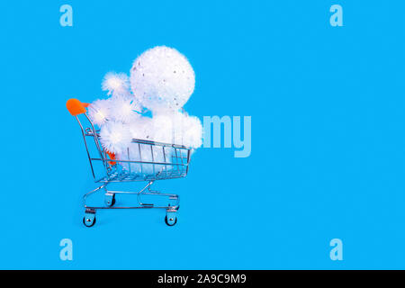 Trolley mit weißen glitzernden Kugeln und glühenden Lichter Kranz. Holiday Shopping, Winter verkauf Metapher. Neues Jahr Feier, Konsumismus symb Stockfoto