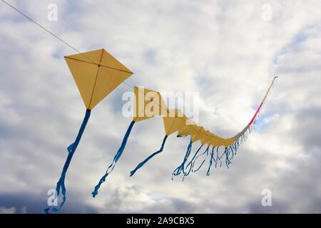 Drachen Zug des gelben Drachen mit blauen Bändern gegen einen grauen Himmel. Bild mit kopieren. Stockfoto