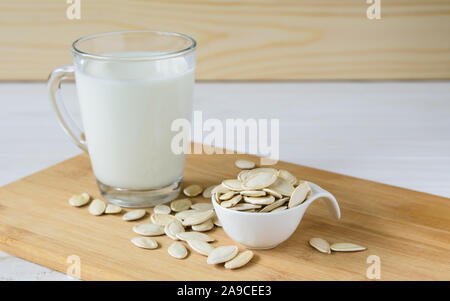 Close-up, Kürbiskerne und Glas Kürbis Milch auf Holz- Hintergrund Stockfoto