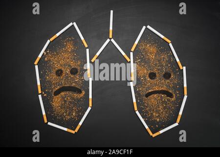 Lungen, die mit Zigaretten und Tabak auf Blackboard zerquetscht Stockfoto