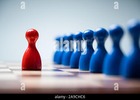 Rote Spielfiguren Vor blauen Bauern auf Schachbrett vor blauem Hintergrund Stockfoto