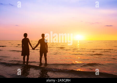 Romantisches Paar am Strand bei Sonnenuntergang Horizont, Hochzeitsreise urlaub Urlaub am Meer, Silhouette der beiden Liebenden Hand hält Stockfoto
