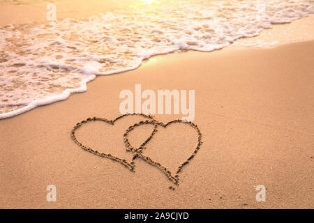 Romantische Hochzeitsreise Urlaub oder Valentinstag am Strand Konzept mit zwei Herzen in den Sand gezeichnet, tropische Zufluchtsort für Paare, Liebe Symbol Stockfoto
