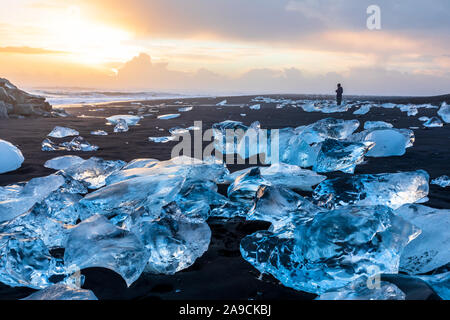 Diamond Beach in Island mit blauen Eisberge schmelzen auf dem schwarzen Sand und Eis glitzernden mit Sonnenaufgang Sonne Licht, Touristen auf der Suche nach schönen Arktis n Stockfoto