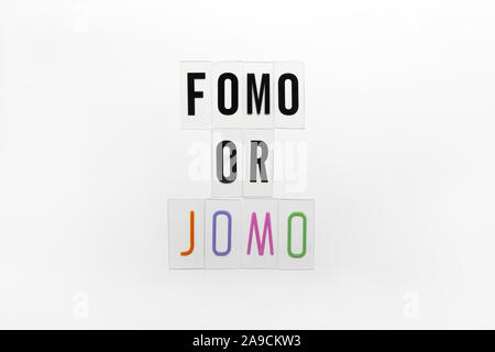 Abkürzung Worte FOMO, JOMO auf transparenten Kunststoff auf weißem Hintergrund. FOMO bedeutet Angst vor fehlenden heraus. JOMO - Freude fehlt. Opposition, Choic Stockfoto
