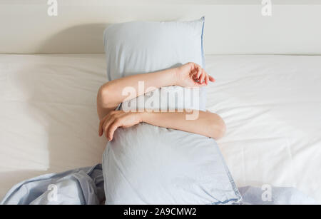 Teil der Home oder hotel Interieur, Frau schlafen auf einem weißen Bett mit blauen Handtücher am Morgen, Frau, deckte sich mit einem Kissen Stockfoto