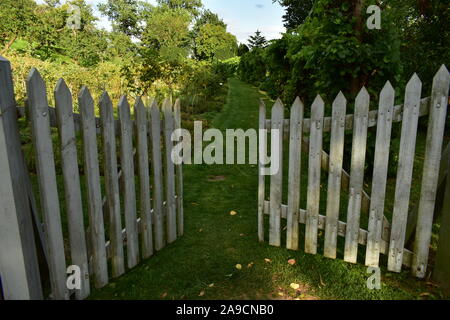 Weißen Lattenzaun Tor, die Zugang zu Gras weg im grünen Garten Stockfoto