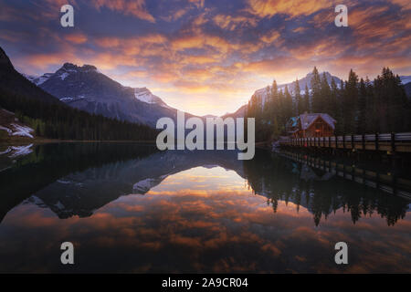 Sonnenaufgang am Emerald Lake, ein Juwel in den Rockies. Spiegelbild, bunte Wolken, eine Kabine und die Bäume. Kleines Haus am Ende der Brücke. Yoho. Stockfoto