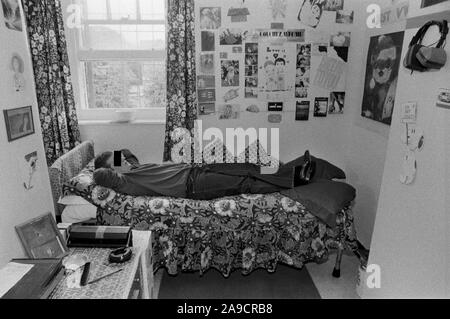 Frau in Gefängniszelle UK 1980 Weibliche Häftlinge, die auf dem Bett lag, mit ihren Besitztümern, Fotos und Zeichnungen, die als Dekoration an der Wand ihrer Zelle festgehalten wurden. HM Gefängnis Styal Wilmslow Cheshire England 1986 HOMER SYKES Stockfoto