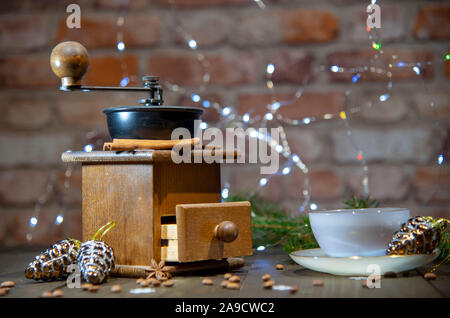 Eine alte manuelle Kaffeemühle und eine Porzellan Schale gegen eine Mauer. Neue Jahr im Loft-Stil. Stockfoto