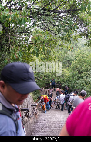 Huashan, China - August 2019: Touristen klettern auf- und absteigend die Treppe auf einen steilen Berg Trail im Norden und Westen Berg Huashan Doppelzi. Stockfoto