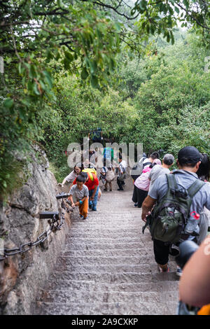 Huashan, China - August 2019: Touristen klettern auf- und absteigend die Treppe auf einen steilen Berg Trail im Norden und Westen Berg Huashan Doppelzi. Stockfoto