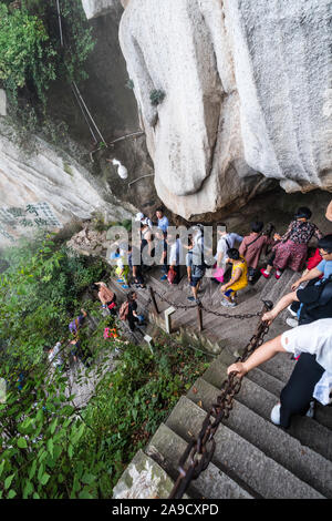 Huashan, China - August 2019: Touristen klettern auf- und absteigend die Treppe auf einen steilen Berg Trail im Norden und Westen Berg Huashan Doppelzi. Stockfoto