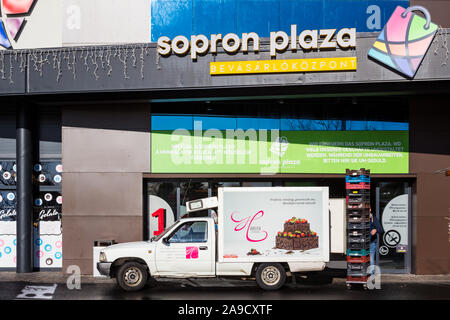 Sopron Plaza Shopping Center vorne in der Mitte mit kühllastwagen von Hoffer muhely (Sweet Shop und Werkstatt) geladen werden, Sopron, Ungarn Stockfoto