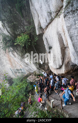 Huashan, China - August 2019: Touristen klettern auf- und absteigend die Treppe auf einen steilen Berg Trail im Norden und Westen Berg Huashan Doppelzi. Stockfoto