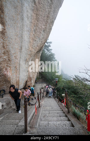 Huashan, China - August 2019: Touristen klettern auf- und absteigend die Treppe auf einen steilen Berg Trail im Norden und Westen Berg Huashan Doppelzi. Stockfoto