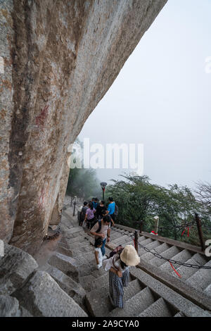 Huashan, China - August 2019: Touristen klettern auf- und absteigend die Treppe auf einen steilen Berg Trail im Norden und Westen Berg Huashan Doppelzi. Stockfoto