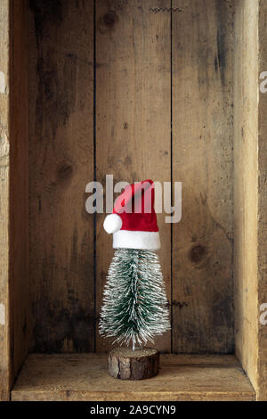 Weihnachtsdekoration Weihnachtsmann Mütze und Baum in einer Holzkiste Hintergrund Stockfoto