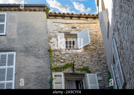 Eine langhaarige orange tabby Hauskatze schaut von einer zweiten Geschichte Fenster in der mittelalterlichen Stadt Saint Paul de Vence, Frankreich. Stockfoto