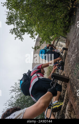 Huashan, China - August 2019: Touristen klettern auf der Vertikalen, steil, schneiden Sie in felsigen Rand Treppen auf einem Berg Trail im Norden und Westen Peak auf Stockfoto