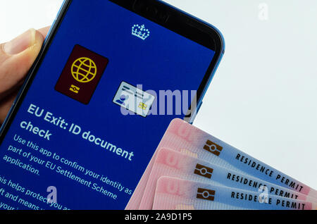 Aufenthaltserlaubnis Karten neben Großbritannien EU Ausfahrt ID-Dokument prüfen App auf dem Bildschirm des Smartphones halten in der Hand. Stockfoto
