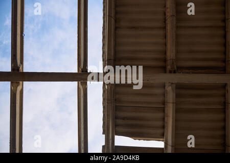 Teilweise zerstört Dach eines alten Gebäudes, durch die ein blauer Himmel sichtbar ist. Stockfoto