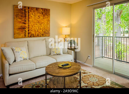 Eine Wohnung Wohnzimmer verfügt über eine Schiebetür zum Balkon im Herbst Wald Wohnung Wohnungen in Mobile, Alabama. Stockfoto