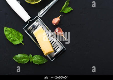 Dreieck Stück Parmesan auf dem Reibeisen, Knoblauch, grüne Basilikum. Zutaten für die Herstellung von Pasta, Spaghetti, Pizza, Bruschetta, Fettuccine, Pesto sa Stockfoto