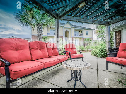 Plüsch Kissen sorgen eine gemütliche Sitzecke unter der hölzernen Pergola Terrasse Abdeckung am Cypress Cove Apartment Wohnungen in Mobile, Alabama. Stockfoto