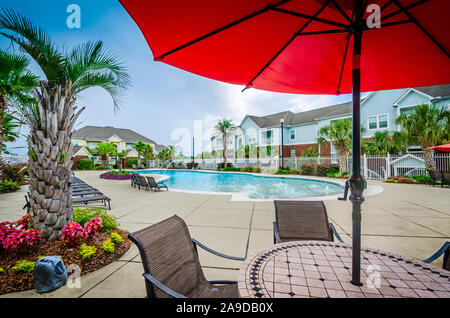 Ein Sonnenschirm Schattierungen einer Tabelle durch die eingebaute Swimmingpool am Cypress Cove Apartment Wohnungen in Mobile, Alabama. Stockfoto