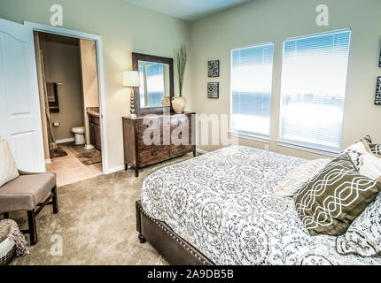 Ein Hauptschlafzimmer mit Badezimmer wird dargestellt im Cypress Cove Apartment Wohnungen in Mobile, Alabama. Stockfoto