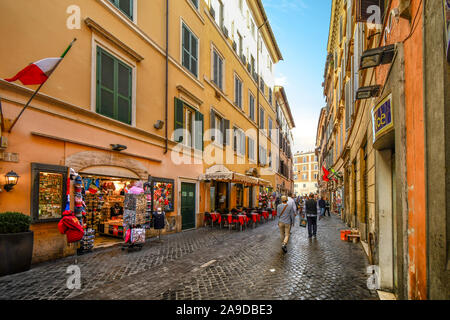 Ein kopfsteinpflaster Straße mit Bürgersteig Cafés und Souvenirläden im historischen Zentrum von Rom, Italien Stockfoto