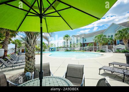 Ein Sonnenschirm Schattierungen einer Tabelle durch die eingebaute Swimmingpool am Cypress Cove Apartment Wohnungen in Mobile, Alabama. Stockfoto