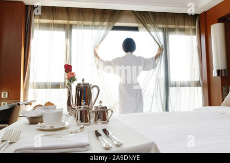 Die junge Frau in einem Hotelzimmer für Kaffee Stockfoto