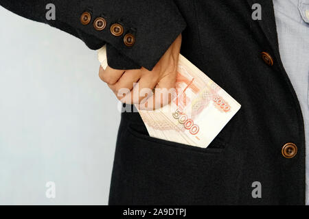Bärtige Geschäftsmann in dunklen Anzug entfernt Russische Rubel Banknoten zu seinem Anzug Tasche. Finanzielle Thema. Man scheine in der Tasche. Gehalt. Stockfoto