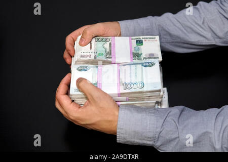 Anonyme Unternehmer erreichen, die Hand Geld zu schnappen, Russische Rubel Währung, in einem dunklen Zimmer. Männliche Hände ergriff eine große Summe Geld Stockfoto