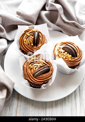 Kleine Kuchen oder Muffins mit Schokoladencreme auf weißem Holz- Hintergrund. Urlaub kuchen Feier, leckeres Dessert Stockfoto