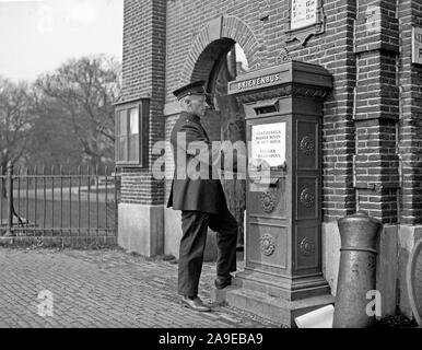 Eine Post Arbeiter sticks ein Plakat an den Briefkasten "Briefmarken in der rechten oberen Ecke in die Ecke schneller Versand" Stockfoto