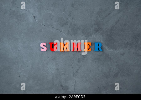 Die bunten Sommer Wort ist aus Holz Buchstaben auf einem grau verputzte Wand Hintergrund gemacht Stockfoto