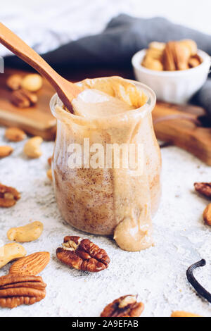 Mandel, Pecan und Cashew-nuss Butter in Glas. Hausgemachte organischen gemischte Nüsse Paste mit Zimt und Vanille auf weißem Hintergrund. Gesunde natürliche Stockfoto