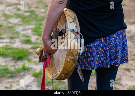 Eine Nahaufnahme der Hand einer Frau mit einem traditionellen einheimischen Trommel, Drumsticks und Holzstücke, während einer Musik Feier im Park Stockfoto