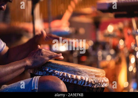 Nahaufnahmen der Hände des Menschen, die auf der afrikanischen djembe Trommel, selektiver Fokus auf Händen mit verschwommenen Hintergrund während einer traditionellen Musik Performance Stockfoto